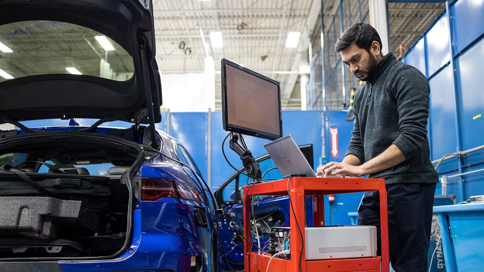 Multimatic Electronic Systems - Man working on a computer by a vehicle